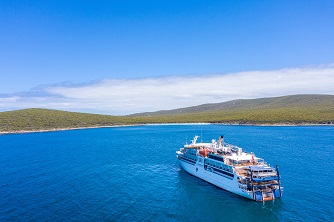 A small expedition cruise vessel sailing into Memory Cove on the Eyre Peninsula, South Australia on a clear, sunny day